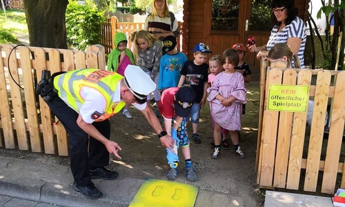 Polizeikommissar Ralf Buchmeier (Verkehrssicherheitsberater der PI Goslar) sprüht zusammen mit den Kindern die "Gelben Füße". Foto: Polizei Goslar