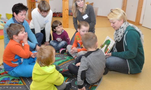 Petra Winter (links) und Annette Scheunemann (Zweite von links) aus Uehrde hospitierten im Lebenshilfe-Kindergarten Siebenstein in der Schmetterlingsgruppe, wo die Erzieherin Wiebke Tolle (rechts) den Kindern ein Bilderbuch zeigt. Foto: Lebenshilfe