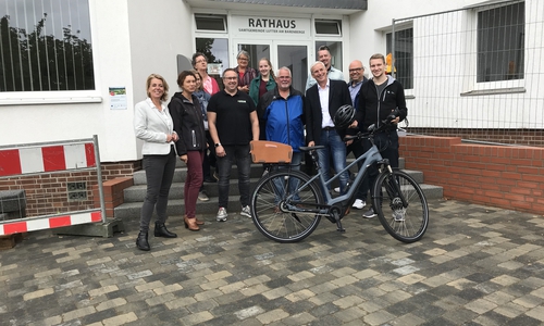 Andrea Keßler, Regionale EnergieAgentur, Antje Klimek, Kommunalmanagerin von Avacon und Samtgemeindebürgermeister Bodo Mahns lassen sich zusammen mit den Mitarbeitern der Gemeindeverwaltung von Guido Kasten (von E-Bike Kasten) das Rad und dessen Handhabung erklären. Foto: Regionale EnergieAgentur e.V.                                             
