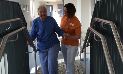 Zunächst ein Fuß auf die unterste Stufe – Larissa Klassen (rechts) übt mit Ingeborg Kokott das Treppensteigen. Foto: Helios