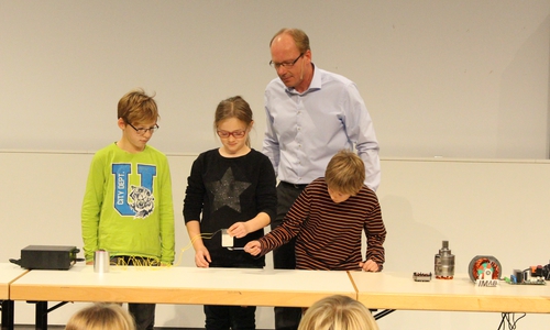 Professor Dr. Markus Henke erklärt Bennett, Johanna und Finn die Funktionsweise eines Elektromagneten.