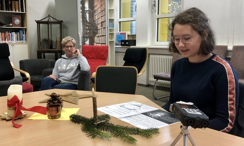 Hanna liest konzentriert ihren Adventskalendertext für die Aufnahme vor. Michaela Drexler hört im Hintergrund interessiert zu.