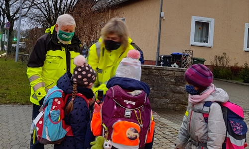 Klaus Seiffert von der Verkehrswacht und Silke Hitschfeld von der PI Wolfsburg-Helmstedt bei der Übergabe von Reflektionsmaterial an die Grundschulkinder.