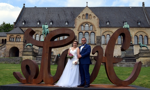 Ein Brautpaar posiert an der LoveHate-Skulptur vor der Kaiserpfalz.