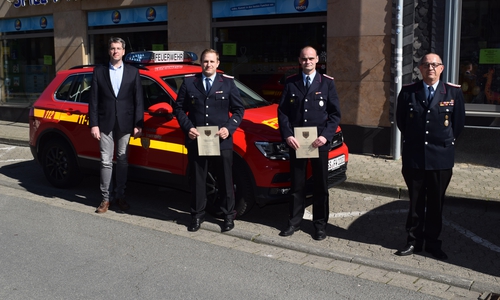 (von links) Oberbürgermeister Dr. Oliver Junk, Sebastian Rau, Kai Schmidt und Stadtbrandmeister Christian Hellmeier stehen gemeinsam vor einem Einsatzwagen der Feuerwehr.