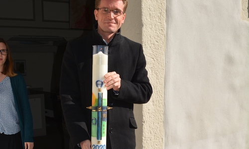 Pastor Carsten Dellert bringt die Osterkerze vor die Kirche.