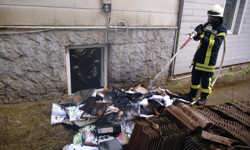 Die Feuerwehr löscht die brennenden Materialien im Freien ab.