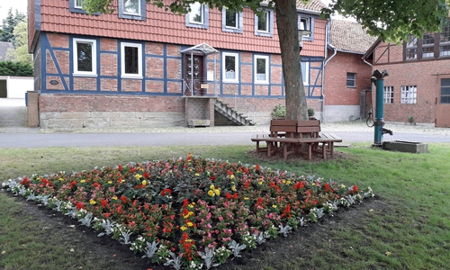 Der Pumpenplatz lädt mit historischer Pumpe, Brunnen und Rundbank und Blumenbeet zum Verweilen ein.