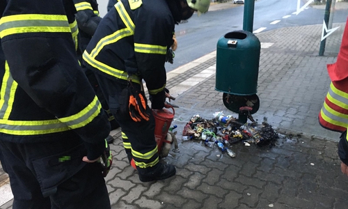 Die Feuerwehr löscht den brennenden Inhalt eines Abfalleimers mit einer Kübelspritze.