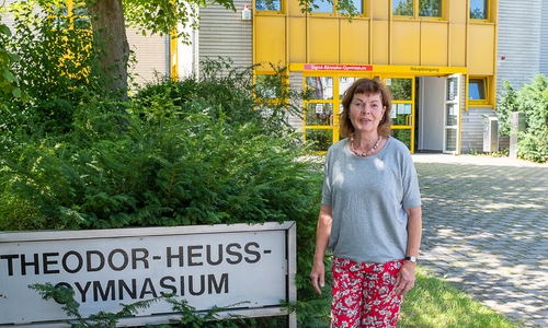 Sigrid Rönneke vor ihrer langjährigen Wirkungsstätte, an der man sie ungern gehen lasse. Über der Tür der Schriftzug Sigrid-Rönneke-Gymnasium - Ein letzter Gruß des Kollegiums.