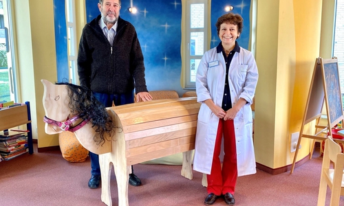 Gerhard Kupka (li.) übergibt sein selbst gebautes Holzpferd an Chefärztin Prof. Dr. Jacqueline Bauer. 