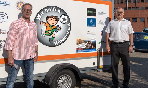 Volker Machura und Volker Warnecke, Leiter der Polizeiinspektion SZ/WF/PE vor dem Anhänger des Vereins "Wir helfen Kindern".