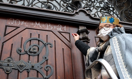 Sternsingerin Chantal schreibt den Segen an die Rathaustür.