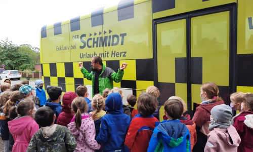 Hendrik Schmidt-Mühlen demonstriert den Erstklässlerinnen und Erstklässern die Kraft des rollenden Busses. 