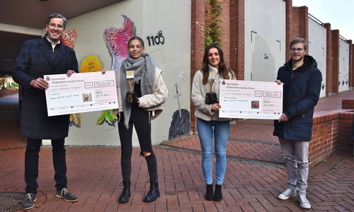 Die Erstplatzierte Shaunyshiwa (2.v.re.) und die Zweitplatzierte Laura  nehmen ihre symbolischen Schecks und Malutensilien von Oberbürgermeister Dr. Oliver Junk (links) und Stadtjugendpfleger Joshua Friederichs vor den Wänden entgegen, die sie  im Frühjahr mit ihren Werken verschönern werden. 