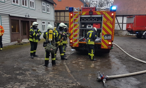 Einsatzkräfte unter Atemschutz vor dem Abbruchhaus (links). 