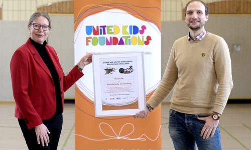 Nicole Mölling, Leiterin der Direktion Salzgitter bei der Volksbank BraWo und Botschafterin des Kindernetzwerks United Kids Foundations, gratuliert zum Gewinn der ersten step BraWo- Bewegungschallenge und überreicht das Preisgeld in Höhe von 150 Euro und eine Siegerurkunde an die Klasse 4c und den Schulleiter der Markus Mertens von der Grundschule Am Ziesberg.