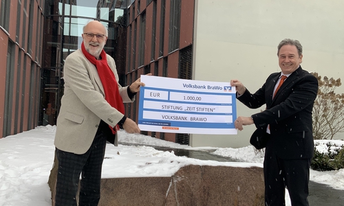 Detlef Tanke, Vorsitzender der Stiftung "ZeitSTIFTEN", nimmt die Spende über 1.000 Euro von Thomas Fast, Leiter der Direktion Gifhorn der Volksbank BraWo, entgegen.