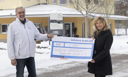 Norbert Preine, Präsident des Vorstandes des Golfclubs, nimmt die Spende symbolisch von Claudia Kayser, Leiterin der Direktion Wolfsburg der Volksbank BraWo, entgegen.