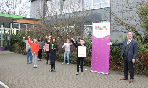 Die anwesenden Schülerinnen und Schüler der Klasse 4c der Hainwaldschule Vöhrum freuen sich mit Klassenlehrerin und step BraWo-Coach Frau Baars über den Pokal des step-BraWo Direktionssiegers in Peine, übergeben von Stefan Honrath (r.), Botschafter des Kindernetzwerks United Kids Foundations und Leiter der Direktion Peine. 