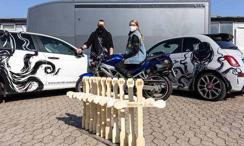 Die Elf Holzkreuze stehen für die Verstorbenen in der Motorradsaison 2020. Im Hintergrund: Marc Kiefer, Geschäftsführer des Messebauers MR - Die Manufaktur und Tina Wachter, stellvertretende Vorsitzende des ACM.