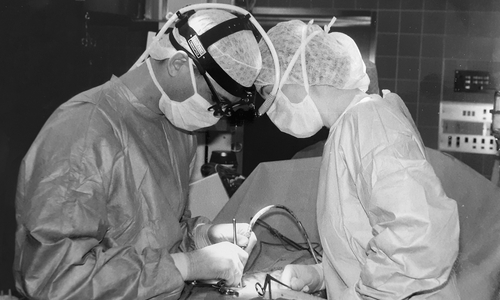 Die erste Bandscheiben-OP am Klinikum im Jahr 1996, noch mit Stirnlampe und Lupenbrille. Links Prof. Sollmann, rechts die Leitende OP-Schwester Ramona Richter.