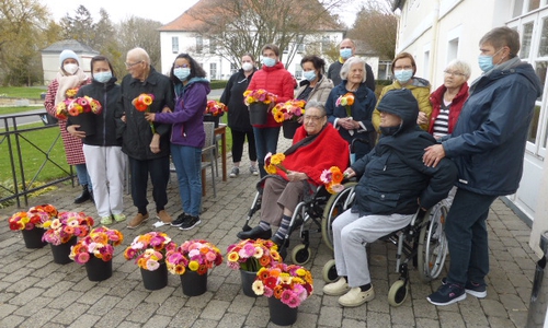 Auf dem Foto die Übergabe der Gerbera-Sträuße von der Jägermeisterstiftung an die Bewohner*innen der Seniorenbetreuung Schloß Schliestedt vor dem Wohnbereich „Langhaus“ (3. von re. Ergotherapeutin Ina Halbe, 5 von re. Pflegedienstleiter Sirko Mros, ganz li. Birgit Lehnhoff, Chefin der Gärtnerei Lehnhoff aus Werlaburgdorf)