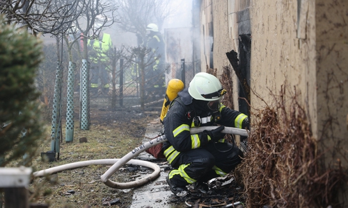 Ein Feuerwehrmann bei den Löscharbeiten am völlig zerstörten Gebäude.