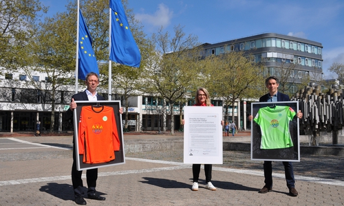 Michael Meeske (r.) übergibt die Regenbogentrikots an Oberbürgermeister Klaus Mohrs und Antje Biniek. 