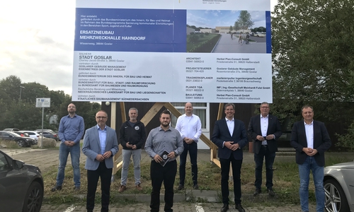 Tobias Brandt (Goslarer Gebäudemanagement GGM), Norbert Schecke (Ratsherr CDU), Joachim Bürdeck (Geschäftsführer SV Hahndorf), Pascal Czwojdrak (Vorsitzender SV Hahndorf), Rüdiger Heine (Vorsitzender RC Germania Hahndorf), Oberbürgermeister Dr. Oliver Junk, Erster Stadtrat Burkhard Siebert und Oliver Heinrich (Betriebsleiter GGM) unter dem neuen Bauschild, das den Beginn der Neubaumaßnahme markiert (v. li.).