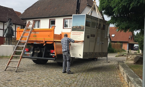 Ein Krahn hebt die mobile Ausstellungsbox an ihren neuen Standort am Hehlinger Roland.