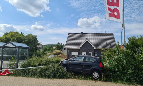 Das Auto fuhr einen Fahnenmast des Supermarktes um.