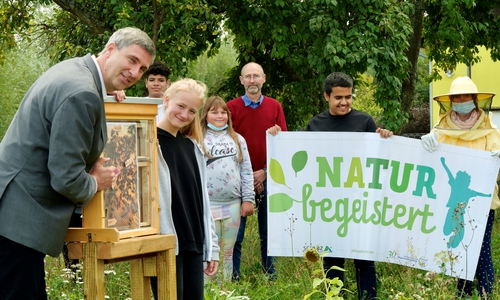 Juliana (12) zeigt Karsten Behr von der Niedersächsischen Bingo-Umweltstiftung die Königin im Schaukasten, hinten sind zu sehen Uwe Schäfer sowie v.l. Rida, Amber, Aikan und Hermine (in Schutzkleidung).