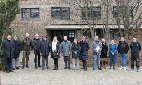Oberbürgermeisterin Urte Schwerdtner (6. v. li.) trifft zum Start der Arbeiten Hans-Joachim Tessner (5. v. li.). Der Termin wird von Politik, Verwaltung, der Tessner-Gruppe sowie zwei Mitarbeitern der Abrissfirma begleitet.