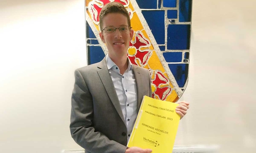 Bürgermeister Tobias Grünert hält den Haushaltsentwurf 2023 für die Gemeinde Vechelde in den Händen.