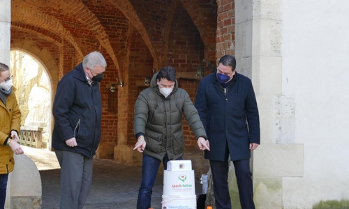 Wolfgang Alexander Paes (Erfinder der Sportstation, Mitte) führt die sportliche Spielekonsole Kreisrat Rolf Amelsberg (links) und Landrat Tobias Heilmann (rechts) auf dem Schlossinnenhof vor. 