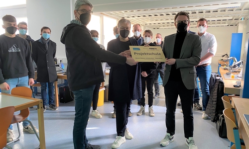 Dezernentin Iris Bothe (Mitte) und Schulleiter Arne Sewing (links) nehmen die offizielle Plakette als Projektschule "Mensch-Roboter-Kollaboration – Robonatives" von Johannes Felbermair vom Niedersächsischen Kultusministerium entgegen.