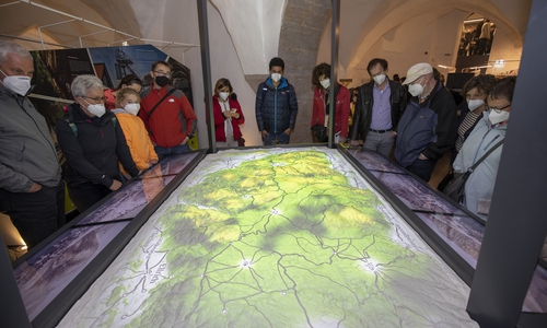 Die ersten Besucherinnen und Besucher verfolgen im Welterbeinformationszentrum am 3D-Modell die Erläuterungen zum Welterbe im Harz.