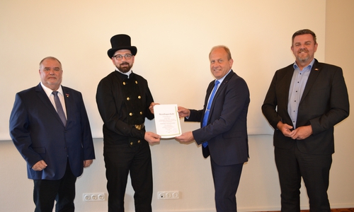 Landrat Radeck händigt Bezirksschornsteinfeger Malak Urkunde aus. Von links: Innungsmeister Dornemann, Bezirksschornsteinfeger Malak, Landrat Radeck, Bürgermeister Busch.