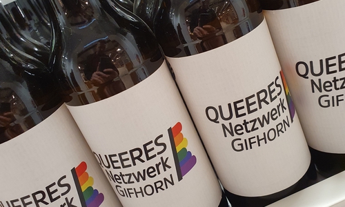 Auf den Flaschen ist das Logo des Queeres Netzwerkes Gifhorn zu sehen.