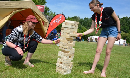 Eileen Kuhne (li.) und Clara Luca Sommer von der Malteser Jugend der Diözese Magdeburg genießen das Pfingstjugendlager beim Jenga-Spiel.