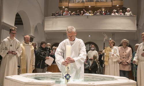 Bischof Heiner Wilmer weiht inmitten des Taufbrunnens das Wasser.  