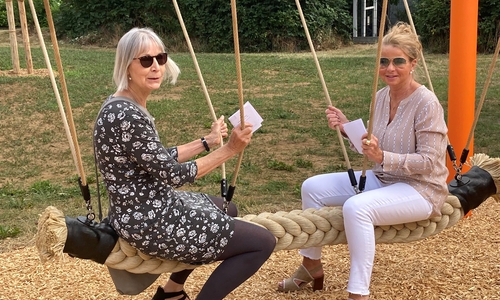 Oberbürgermeisterin Urte Schwerdtner (rechts) und Fachdienstleiterin Karin Jünke testen die neue Tampenschaukel auf dem Spielplatz Saarstraße.