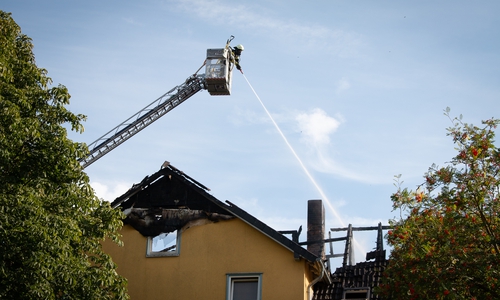 Von der Drehleiter aus löscht die Feuerwehr die immer wieder auflodernden Flammen in der Töpferstraße. Der Dachstuhl des Hauses ist komplett niedergebrannt.