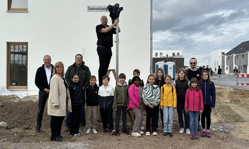 Das erste Straßenschild im Sonnenkamp steht. Mit dabei sind Schüler*innen der Grundschule Hehlingen, Mitglieder des Kinderbeirats, Ortsbürgermeister Philipp Kasten, Geschäftsführer Ihr Haus Sahle Massivbau GmbH Markus Hagedorn und Mitarbeitende der Stadt Wolfsburg.