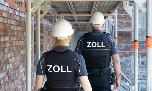 Zöllnerin und Zöllner auf einem Stahlgerüst. Symbolbild