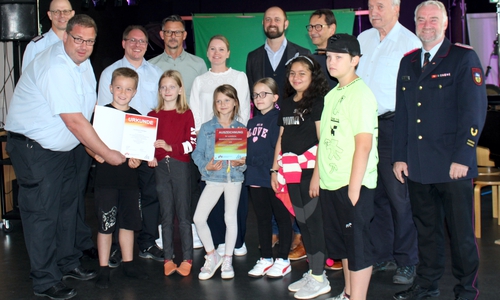Freuen sich gemeinsam mit den Kindern über die Auszeichnung: (v.li.) Michael Barth, Stadtbrandmeister, Michael Lange, Kreisbrandschutzerzieher, Frank Stein, Brandschutzerzieher, Ingo Weitze, Dienstbereichsleiter Ordnungswesen, Madeleine Hollmichel, Konrektorin, Malte Schneider, Bürgermeister, Harald Brötje, Direktor, Karl-Heinz Christ, Brandschutzerzieher im Ruhestand, Oliver Thews, Abschnittsleiter Süd des Kreisfeuerwehrverbandes.