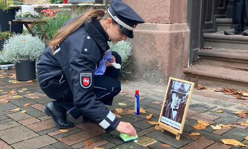 Eine Polizistin pflegt einen der Stolpersteine in de Goslarer Altstadt.