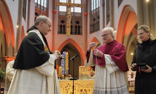 Amtsvorgänger Reinhard Heine (Mitte) übergibt Propst Martin Tenge (links) das von der der Braunschweiger Goldschmiedin Susanne Wittig (rechts) neu geschaffene Propstkreuz.