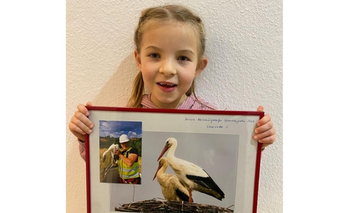 Storchenpatin Charlotte präsentiert stolz das Bild, das sie bekommen hat: Die große Aufnahme zeigt das Elternpaar, die kleine den Storchenvater Ralf Isensee mit Jungstorch „Charlotte“ am Tag der Beringung.